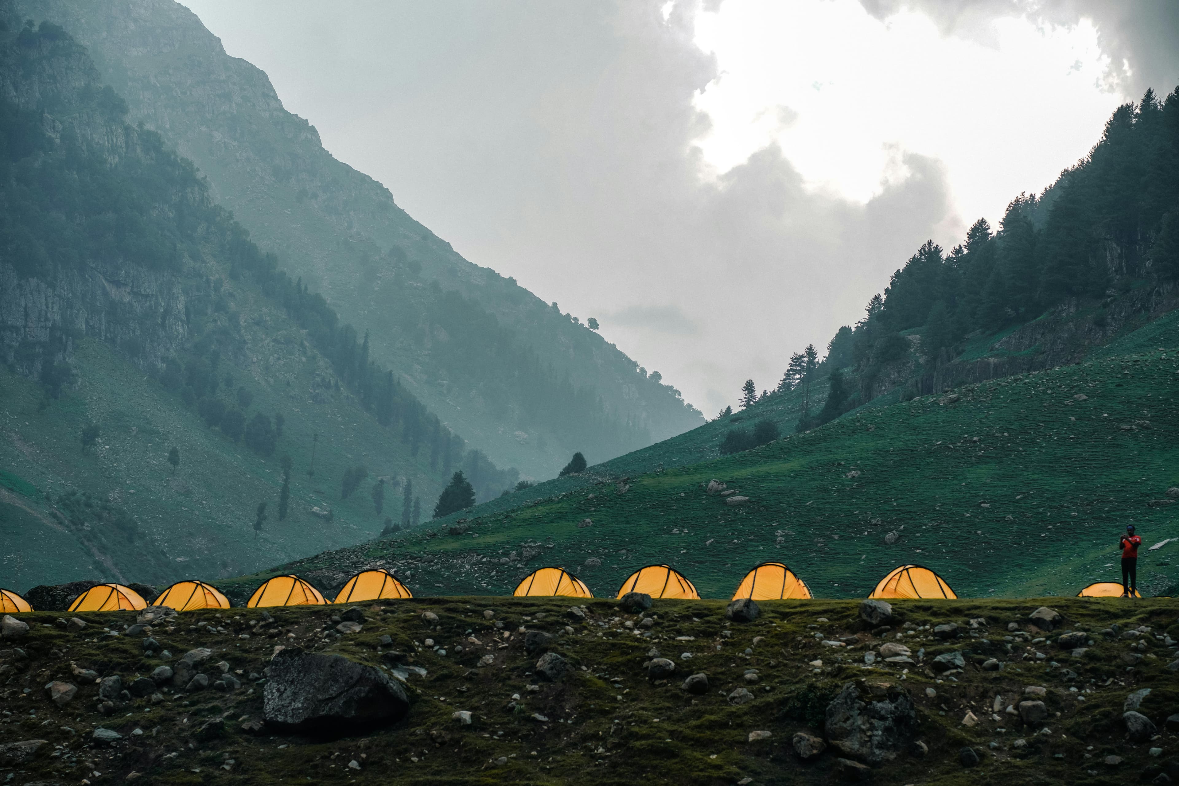 Mountain basecamp with tents beneath misty hills
