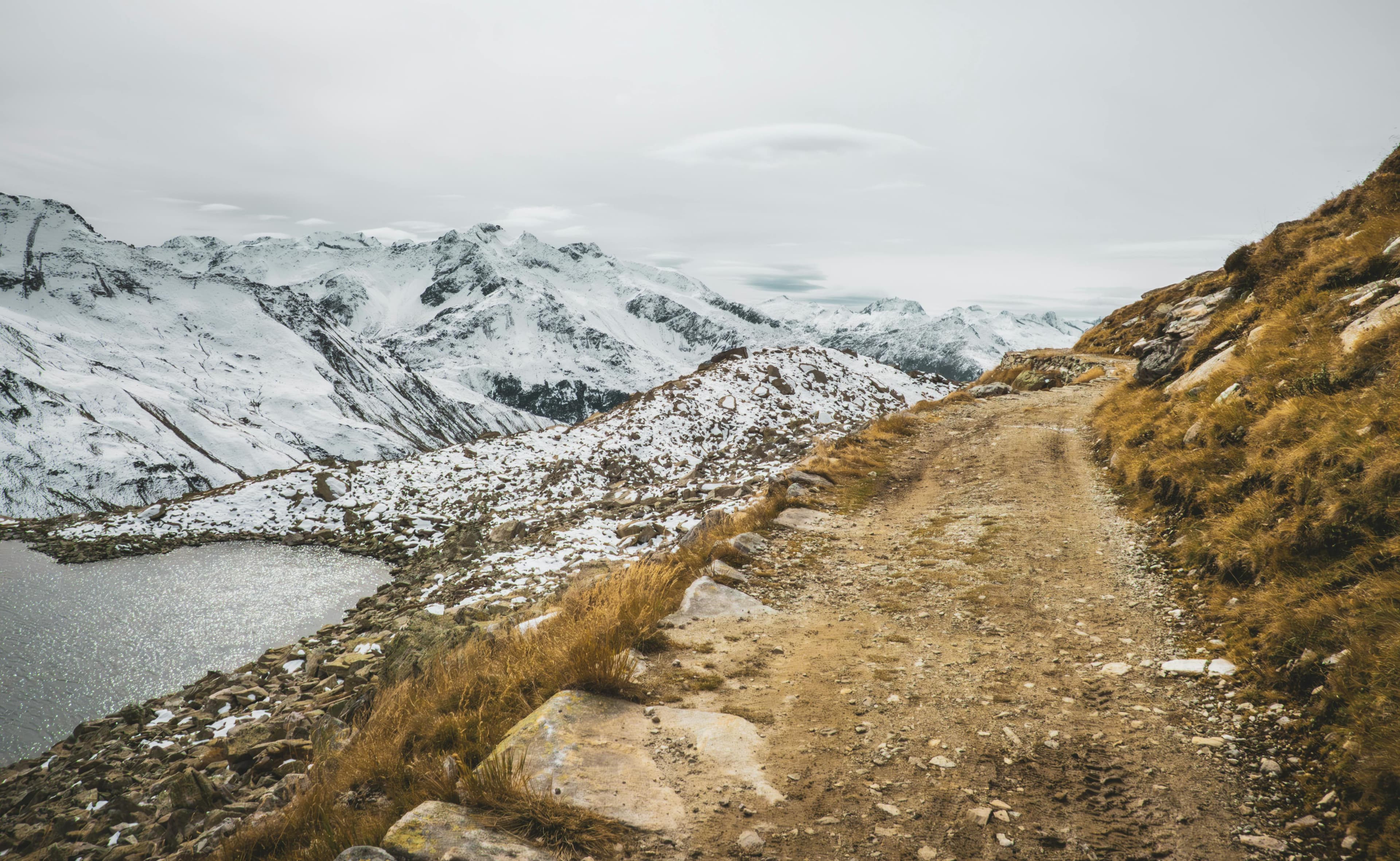 Narrow dirt road across a snowy mountain edge